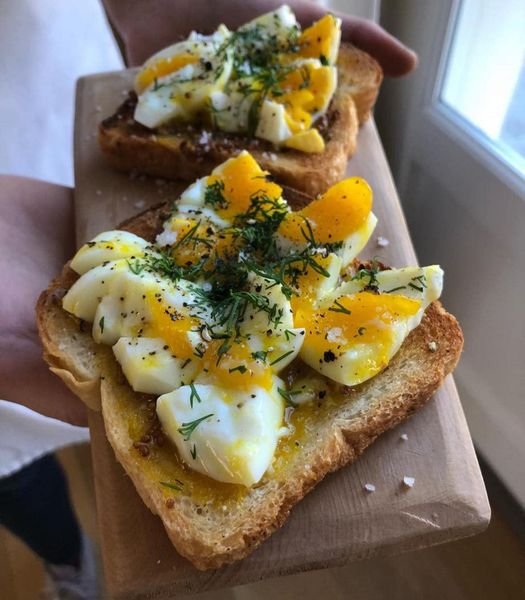 Smashed egg on toast with avocado and herbs on a plate